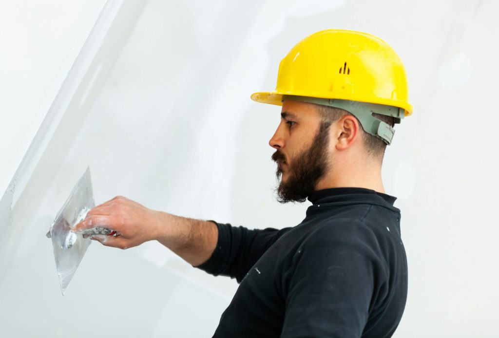 worker plastering gypsum board wall.